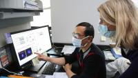 Two researchers review data charts on a computer screen in a lab